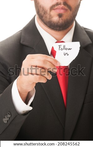 Follow us concept using a man wearing a black suit and red necktie and holding a piece of paper with the text follow us on it.