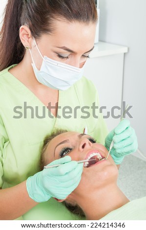 Dentist woman making periodic cavity exam on female patient with perfect teeth