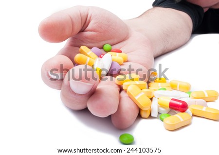 Passed out addict holding a lot of pills in his hand