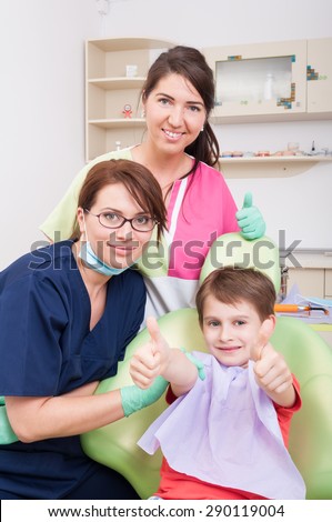 Child patient and dental team showing like or thumbsup in dentist office or cabinet