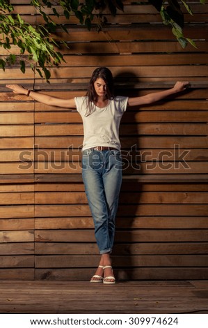 Beautful female model on crucified position wearing white t-shirt and jeans