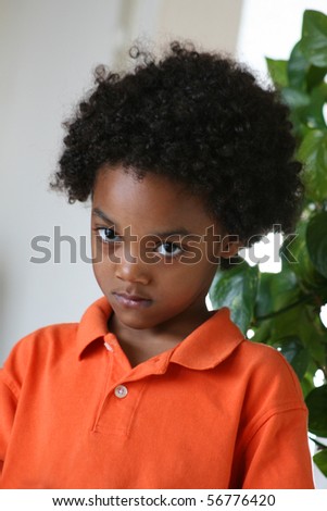 Frontal shot of a young boy looking intense wearing an orange golf shirt.