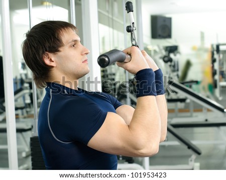 happy cutie athletic guy ,  execute exercise on sport-apparatus  and smile, in  sport-hall