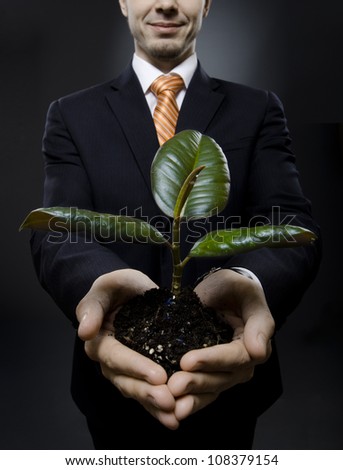 vertical photo  businessman in black costume with  scion  rubber plant