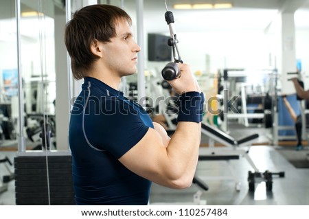 happy cutie athletic guy ,  execute exercise on sport-apparatus  and smile, in  sport-hall