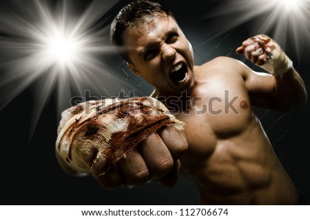 horizontal  photo  muscular young  guy street-fighter, cuff  fist close up on camera and yell , hard light
