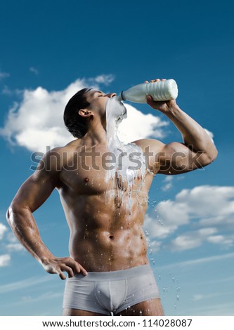 the very muscular handsome sexy guy on sky background, drink milk, focus on face