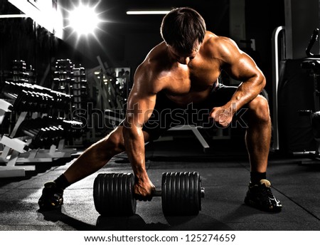 very power athletic guy ,  execute  traction with  dumbbells, exercise on broadest muscle of back, in sport hall