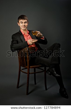 portrait  the  beautiful  businessman with tea, sit on chair without necktie, on dark grey background