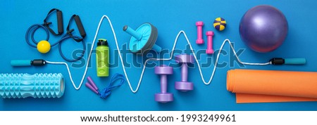 still life of group sports equipment for womens and cardiogram of jump rope, on blue background. Fitness and healthy living, wellness concept.
