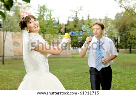 cutie happy married  couple  on nature in park ,  play with soap-bubble and joy smile