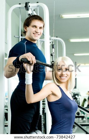 happy cutie athletic girl and guy,  execute exercise on sport-apparatus, in  sport-hall, look on camera and smile