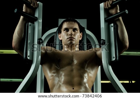 very power athletic guy ,  execute exercise on  on sport-apparatus, in  sport-hall, beauty glamour light