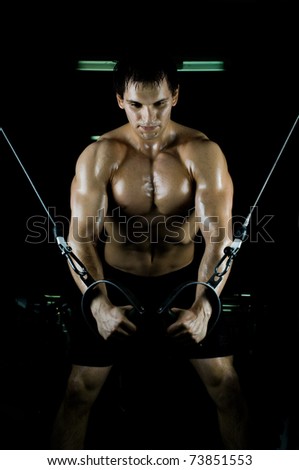 very power athletic guy ,  execute exercise on  on sport-apparatus, in  sport-hall, beauty glamour light