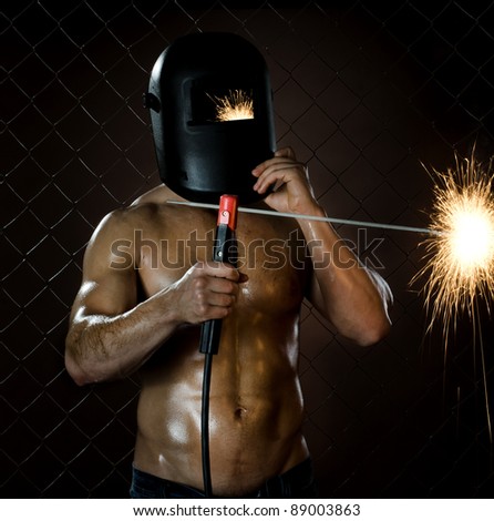 the beauty muscular worker welder  man, weld  electric arc-weld, on netting fence background