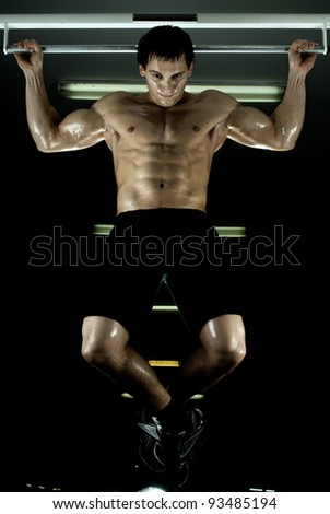 very power athletic guy ,  execute exercise tightening  on horizontal bar, in  sport-hall, glamour light