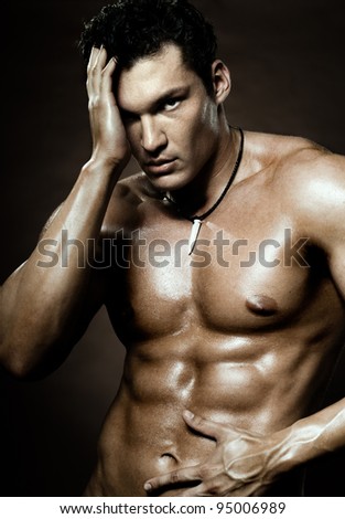 the very muscular handsome sexy guy on dark  brown background, strict