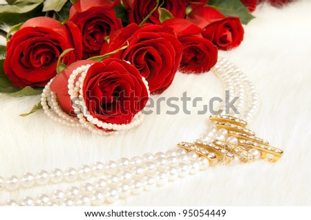Bouquet beautiful red roses and pearl necklace; lay on white to fur