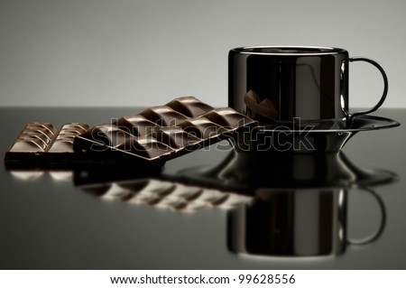still life on mirror with polished surface steel  noggin and chocolate, on dark grey background