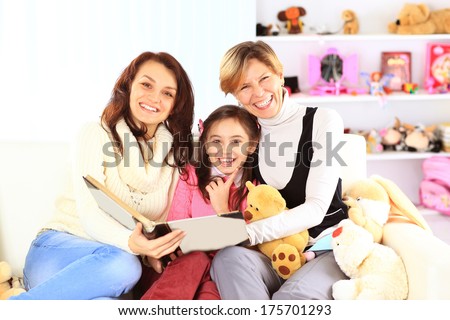 Grandmother, mother, and daughter reading a book together