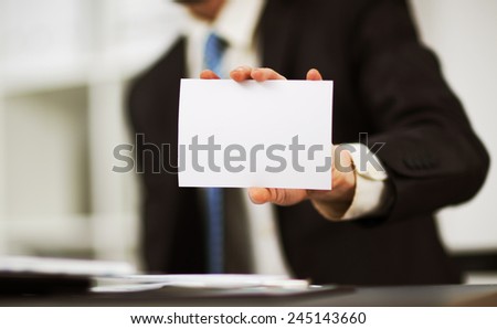 Man\'s hand showing business card - closeup shot on grey background