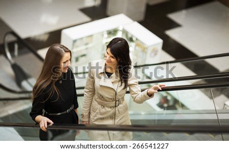 business people on escalator, two young businesswomen talking