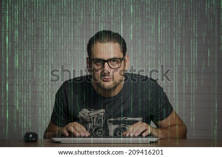 Man sitting in front of his computer, programming binary code passing on the screen.