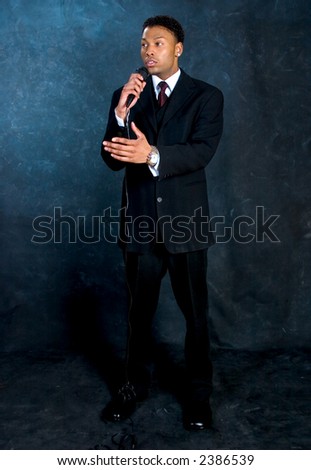 An African American man in a business suit makes a speech.