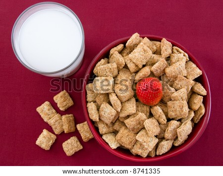 Breakfast Series - Macro shot of a nutritious bowl of shredded wheat squares and strawberries against a red background.