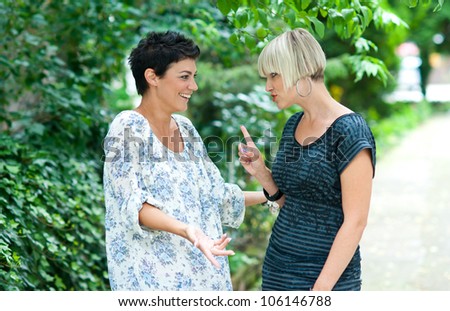 two woman friends chatting outdoors
