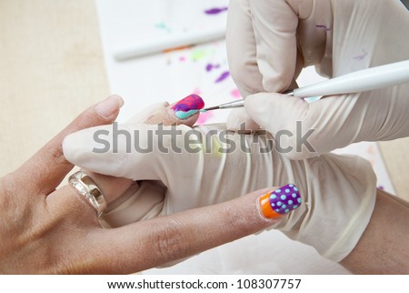 woman nails get painted in manicure salon