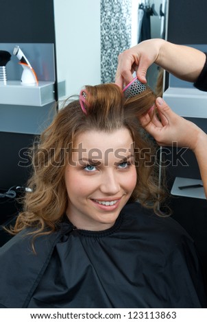 hair stylist putting rollers in woman hair