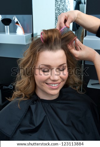 hair stylist putting rollers in woman hair