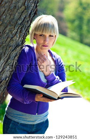 attractive adult woman with book outside