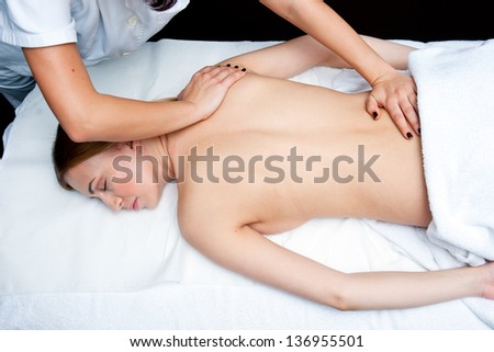 attractive woman on massage table in beauty salon having chiropractic back adjustment
