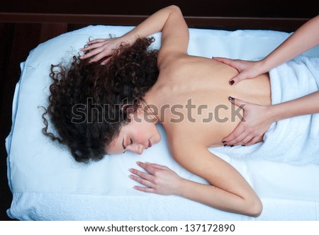 attractive woman on massage table in beauty salon having chiropractic back adjustment