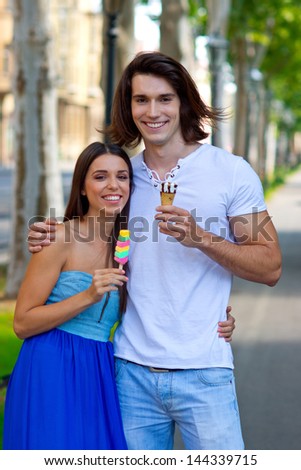 young couple with ice creams walking down the street