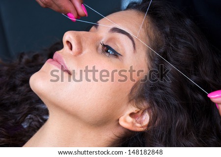 attractive woman in beauty salon on facial hair removal eyebrows threading procedure