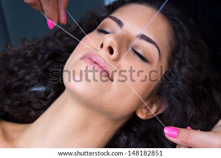 attractive woman in beauty salon on facial hair removal  threading procedure