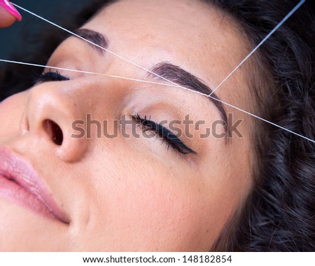 attractive woman in beauty salon on facial hair removal eyebrows threading procedure