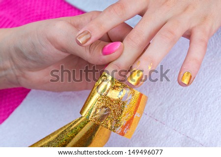 woman hand on manicure treatment with transfer foil in beauty salon