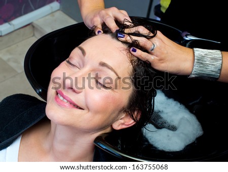 mature woman getting head massage and hair washed in salon