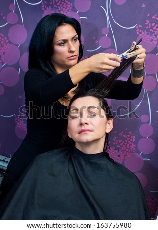 beautician making new hair style to mature woman in salon