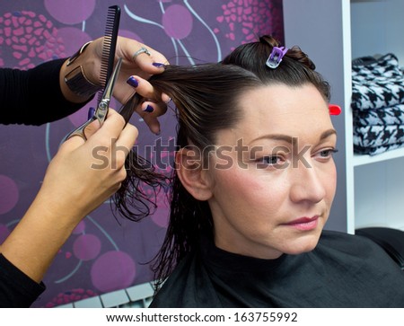 beautician making new hair style to mature woman in salon