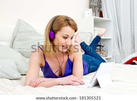 attractive woman in bed with laptop computer and headphones