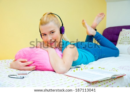 attractive teen girl with headphones listen music from mobile phone in her bed
