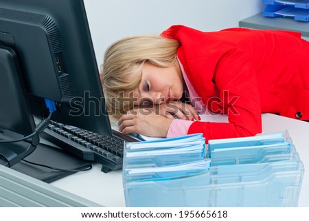 attractive blonde business woman sleeping with head on the desk in office