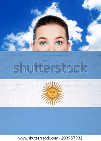 woman peeking behind wall with argentina flag