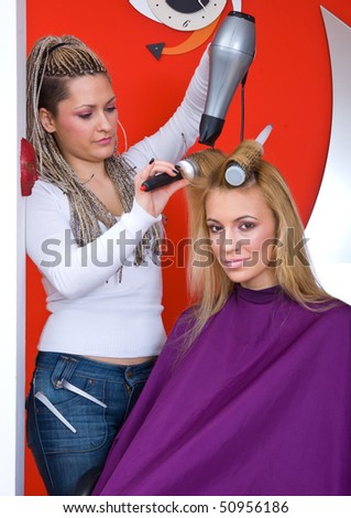 stylist with hair blower work on woman in salon