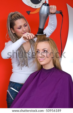 stylist with hair blower work on woman in salon